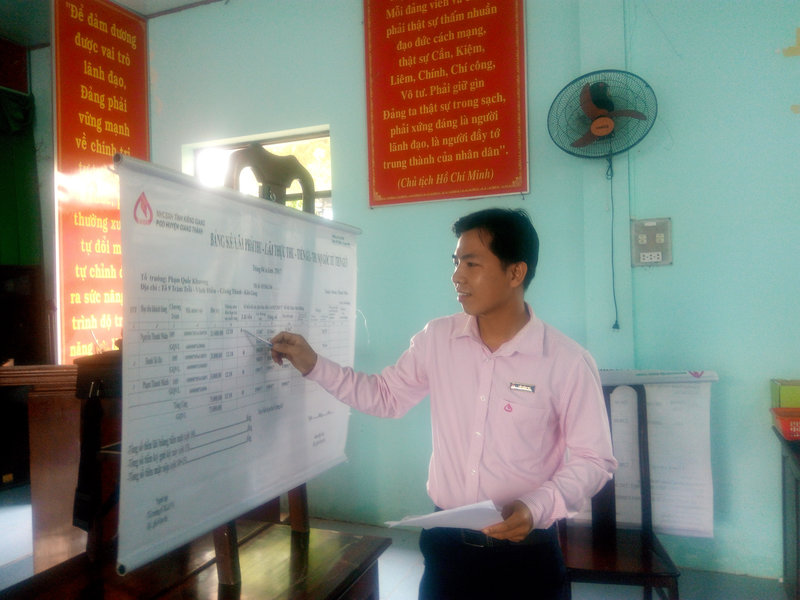 cán bộ NHCSXH hướng dẫn tổ cách ghi chép Bảng kê 13TD khi thu lãi.jpg